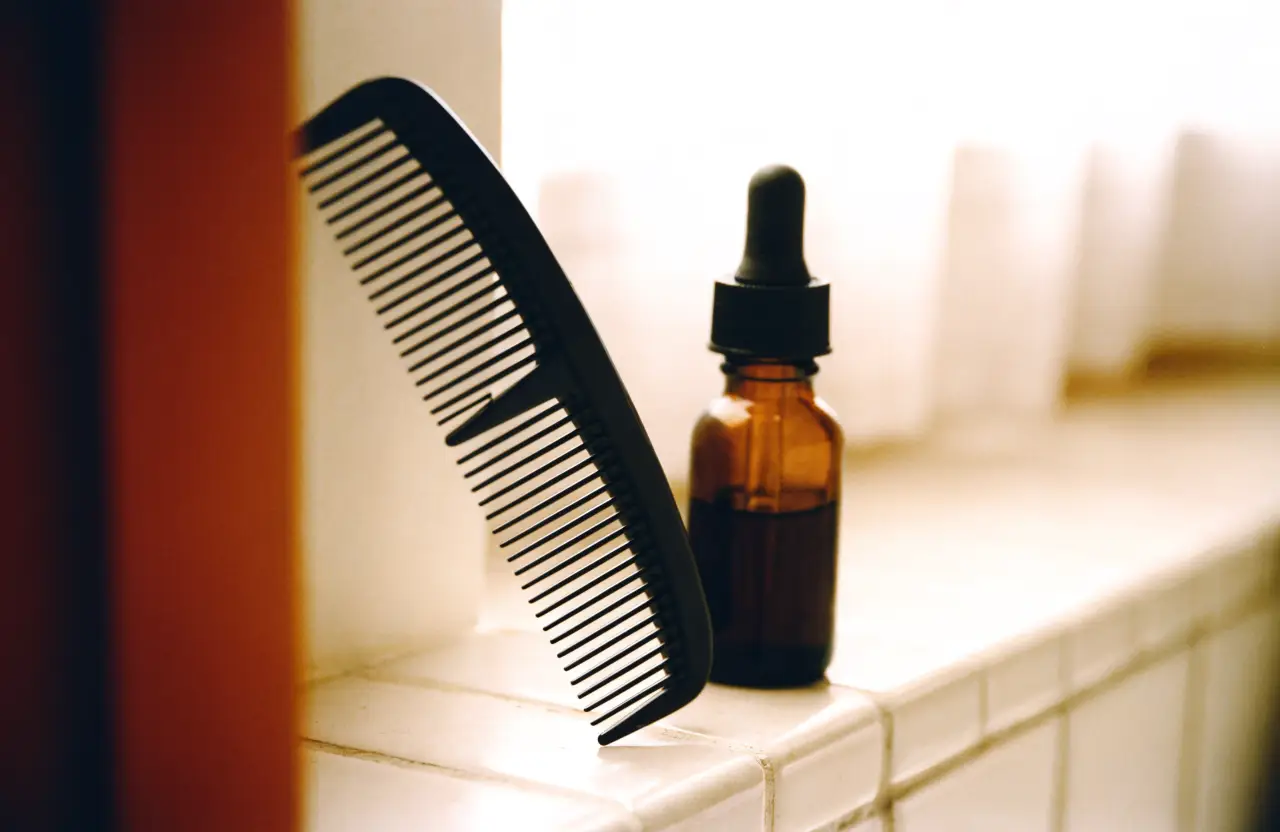 A comb and an amber dropper bottle on a bathroom shelf
